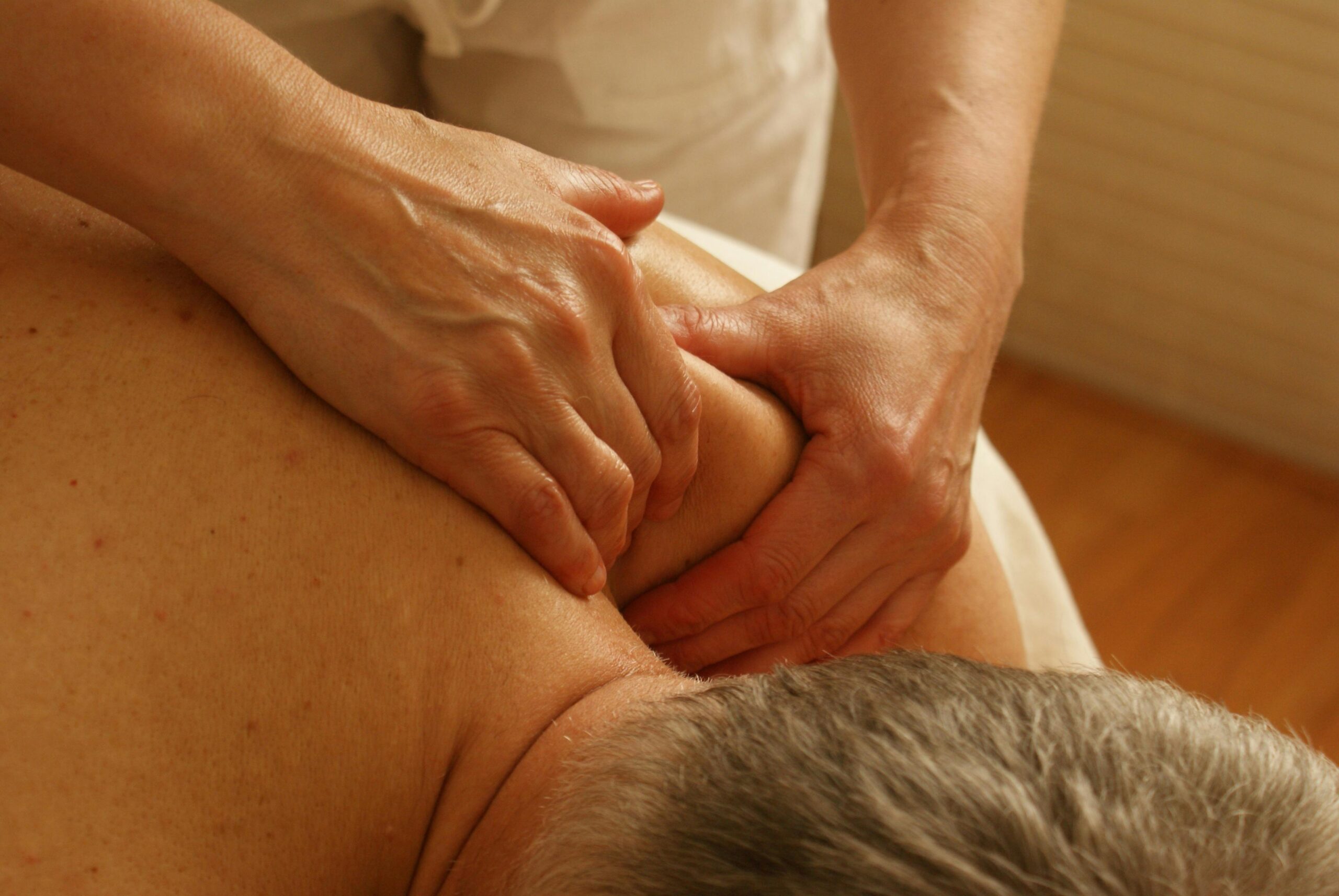 A therapist applying firm pressure to a client's back, highlighting "best massage spa in Kochi" and deep tissue massage